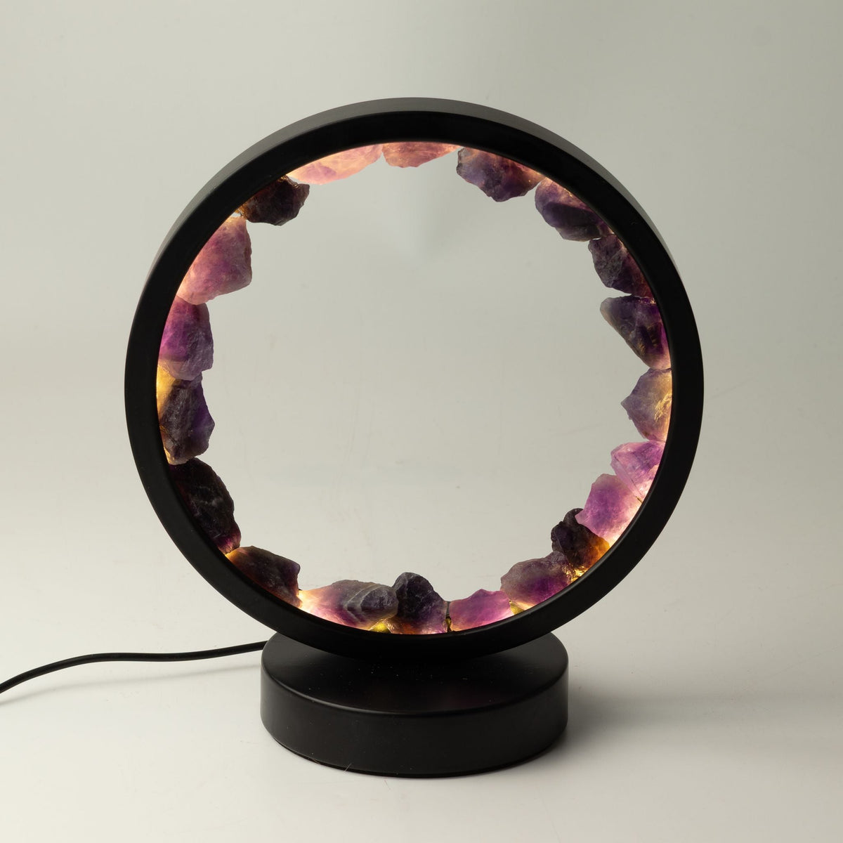 Amethyst gemstone halo lamp with a black circular frame and base.